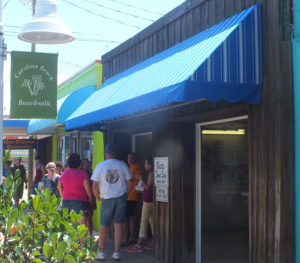 People gather outside the boardwalk's anchor shop, Britt's Donut Shop. Port City Daily file photo.