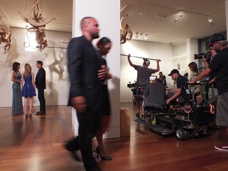 Extras walk by as crew members capture the action during a scene of 'The Longest Ride,' which filmed at Cameron Art Museum this week. Photos by Jonathan Spiers.