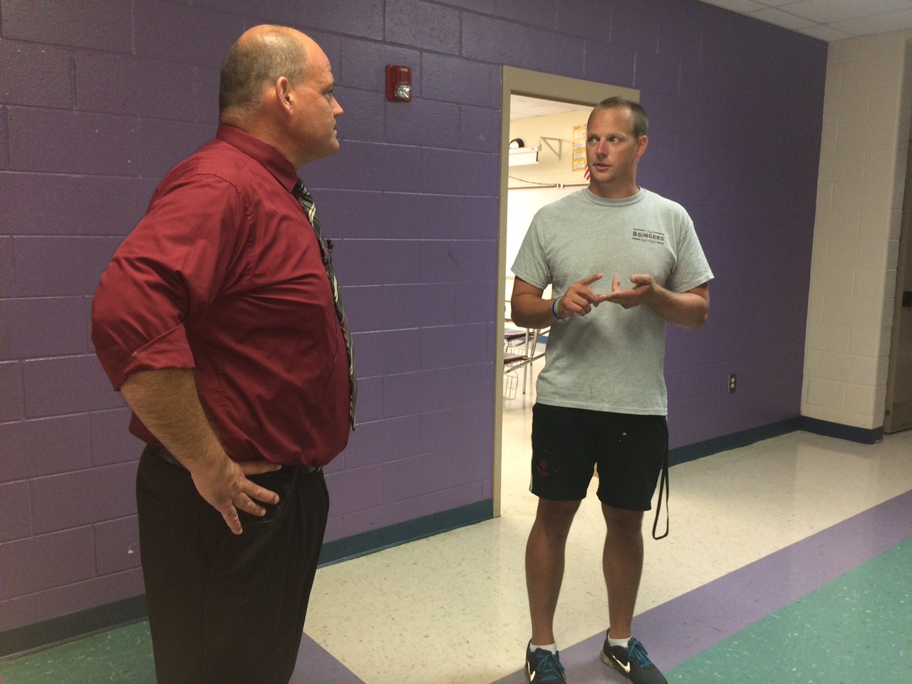 Ashley High School's new principal, Patrick McCarty, talks with a teacher Tuesday. McCarty plans to improve relations with staff, parents and students by spending more time in the hallways than his office. Photos by Hilary Snow.