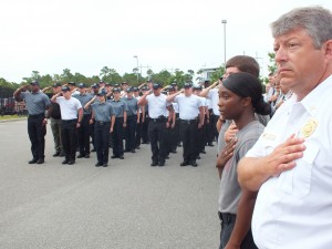 Law enforcement and EMS students stand at attention during a rendition of the National Anthem.