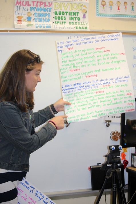 Teacher Margaret McLaurin holds cue cards to prompt students and keep them focused. Students came up with their own questions and did their own research in preparation for the Skype event.