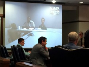 Eduard Patrick (right) on camera with a deputy for his first appearance in district court. Photo by Christina Haley.