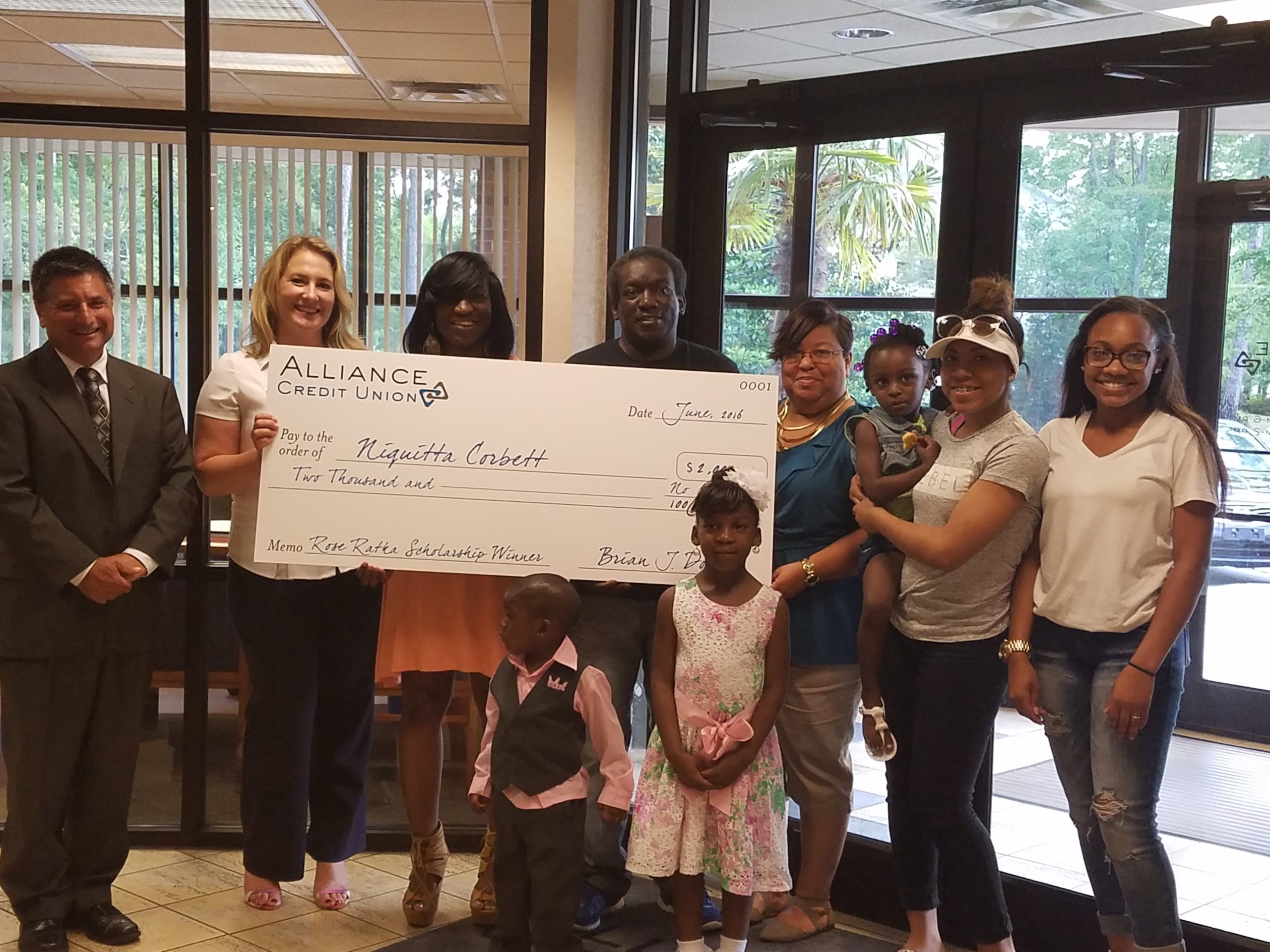 Niquitta Corbett, with her family beside her, receives a $2,000 scholarship from Alliance Credit Union's vice president of sales, Rick DeCrescente and Kandra Romeo, business relationship manager, during a banquet earlier this week. 
