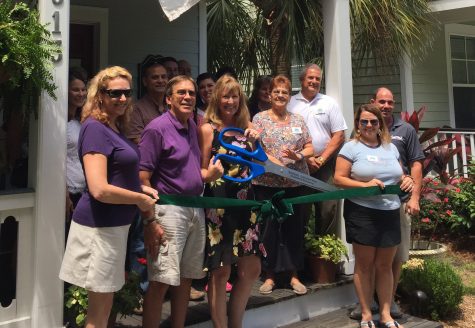 Cathi Ulrich holds the ribbon cutting scissors with her husband Rick (left). They are joined by friends and members of the Southport-Oak Island Area Chamber of Commerce.