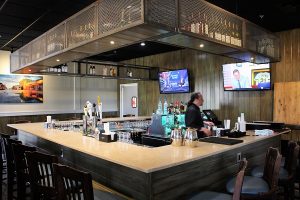 The bar features weathered steel boxes for storing alcohol, almost making it look like the bottles are being stored in crab pots. (Port City Daily photo/CORY MANNION)