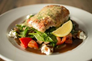 Saltimbocca, one of Cape Fear Seafood's specialties, features the "fresh catch white fish wrapped in prosciutto and served over a bed of sautéed spinach, tomatoes and mushrooms then draped with a classic demi-glace & lemon beurre blanc." (Port City Daily photo/COURTESY CAPE FEAR SEAFOOD COMPANY)