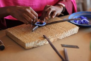 Sarah, one of the Swahili Coast partners, works with an awl to punch the leather. (Port CIty Daily photo/COURTESY CAROLINE FISHER)