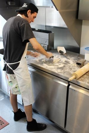Aaron English, grandson of owner Rodney Robbins, hand cuts dough for a fresh batch of beignets. (Port City Daily photo/CORY MANNION) 
