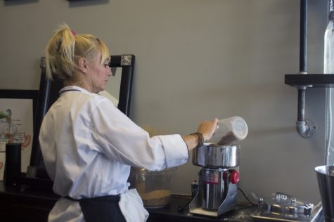 Healing specialist Stacey Maguire grinds einkorn, a whole grain Kefir Complete sources from Tuscany used to produce their 99 percent gluten-free bread. (Port City Daily / JOHANNA FEREBEE)