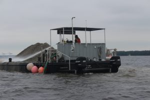 Barges are loaded with recycled concrete and then taken out into the river where they are then sprayed into the water giving oysters a new habitat (Port City Daily photo/MICHAEL PRAATS)