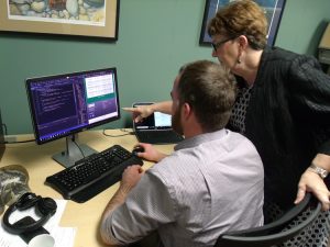 Longtime school teacher and now retired UNCW Professor Debbie Powell works with graduate student Zach Krepps on Uni_SPIRE, a cloud-based tool to help teachers better teach writing skills to students. Almost 170 UNCW students worked with Powell on the project. Krepps is the technology manager. (Port City Daily photo / DAVID DEAN)