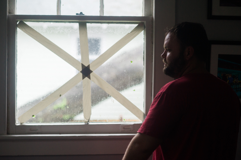 Stacy Ambrose stares out a window of a home in the Carolina Place neighborhood east of downtown Wilmington during the calm between the inner bands of Hurricane Florence Friday morning. Ambrose had earlier evacuated his home in Wrightsville Beach. (Port City Daily photo | Mark Darrough)