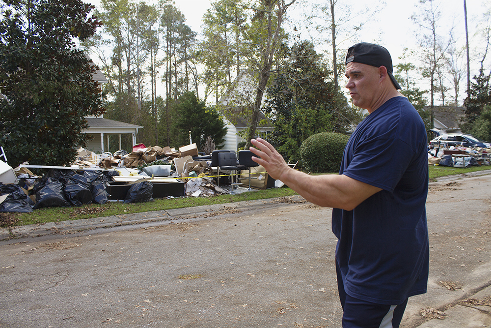 Mark Cerqueira surveys his damaged belonging on the front lawn of his home in Leland, where floodwaters filled over three feet of his home. (Port City Daily photo/Johanna Ferebee)