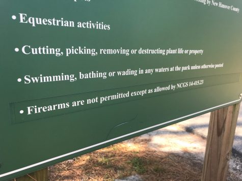County park signs also feature language about the prohibition of firearms, although they are worded in a way that keeps them in compliance with the 2013 state law allowing them in parks under most circumstances. (Port City Daily photo / Benjamin Schachtman)