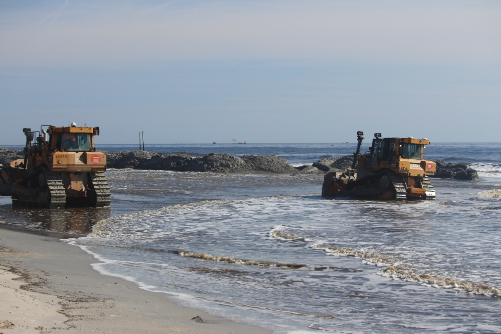 Track-driven earth-moving vehicles in the surf at Carolina Beach helping re-nourish the shoreline (Port City Daily/Michael Praats)