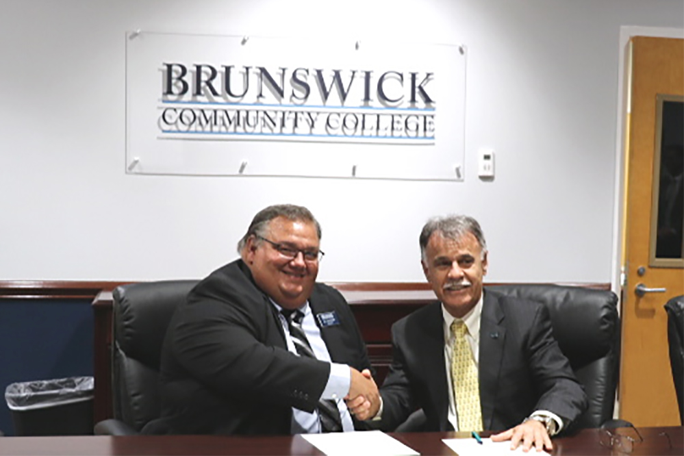 Dr. Gene Smith and Dr. Jose Sartarelli shake hands after signing a letter of intent to expand the two educator's existing partnership this week. (Port City Daily photo/Courtesy Brunswick Community College)