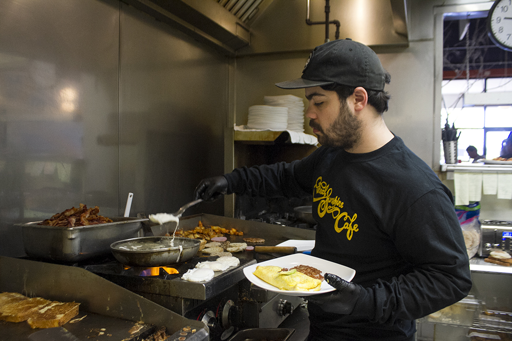 Nick Sambuco moves freshly-poached eggs out of the skillet in Eternal Sunshine Cafe's kitchen. (Port City Daily photo/Johanna Ferebee)
