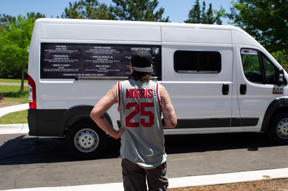 Outside Flying Machine Brewing Company, a customer ponders his different sandwich options on the opening day of Detour Deli's new food truck. (Port City Daily photo/Mark Darrough)