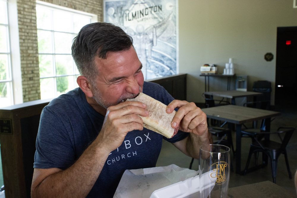 Eric Flores, facilities manager of the Brooklyn Arts Center, enjoys a bite of the Paradisaical. (Port City Daily photo/Mark Darrough)
