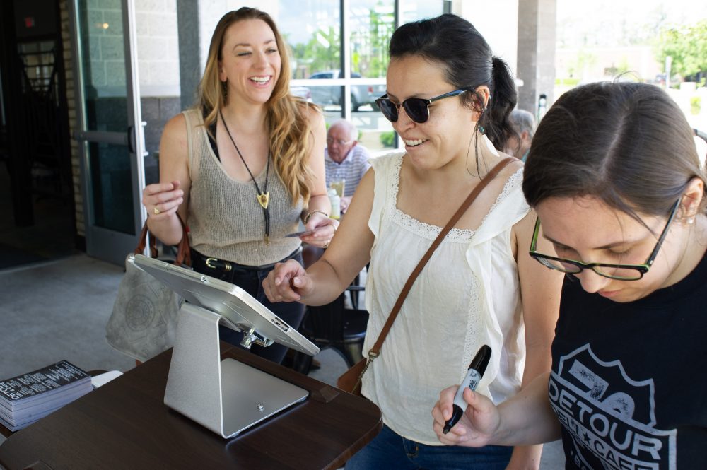 Marisa Dransoff makes her sandwich order using a tablet on the patio outside Flying Machine Brewing Company. (Port City Daily photo/Mark Darrough)