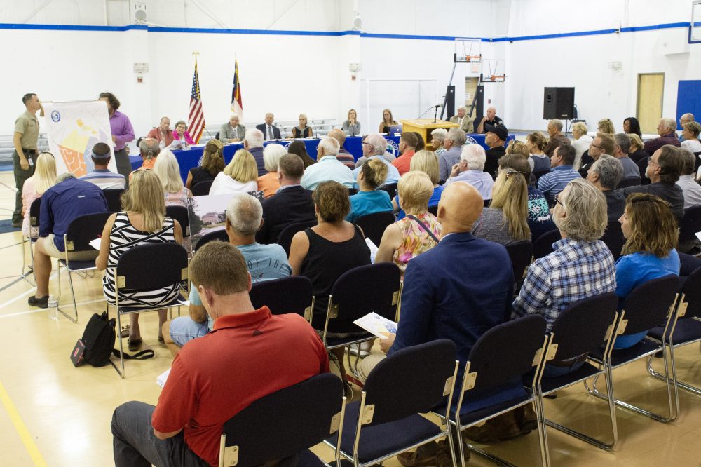 Surf City residents look on as city planning staff hold up a preliminary map of the 346-unit Surf City Crossing luxury apartments. (Port City Daily photo/Mark Darrough)
