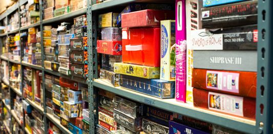 A row of shelves that currently house Darryl Rubin's collection of old and rare games inside the warehouse space behind Cape Fear Games. (Port City Daily photo/Mark Darrough)