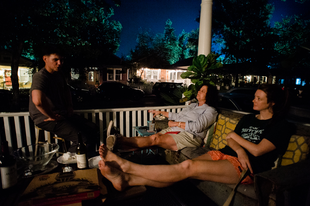 Neighbors talk on a front porch on Wrightsville Avenue as the lights of the film set shine behind them. (Port City Daily photo/Mark Darrough)