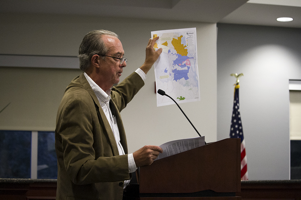 Candidate for H2GO Commissioner Steve Hosmer holds up an annexation map purportedly created by Leland, shared by Belville in a press release, at H2GO's Tuesday meeting.  (Port City Daily photo/Johanna Ferebee)