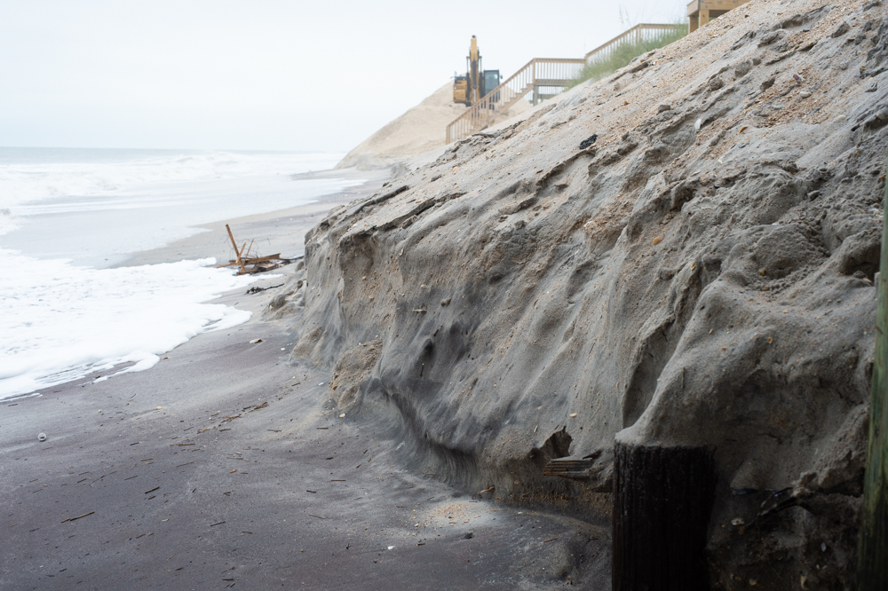 A man walks out in the high tide to surf just north of the Surf City Ocean Pier late Monday morning (Port City Daily photo/Mark Darrough)