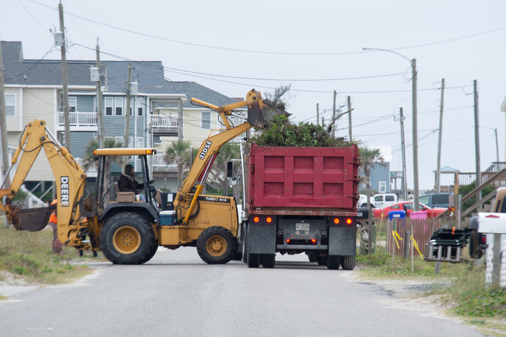 A man walks out in the high tide to surf just north of the Surf City Ocean Pier late Monday morning (Port City Daily photo/Mark Darrough)