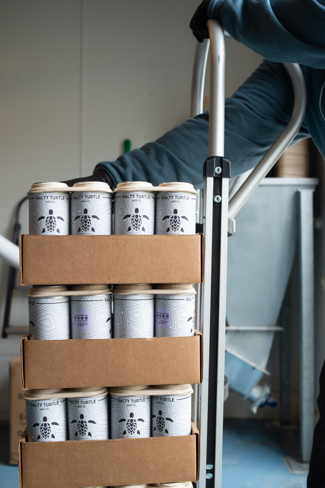 Four-packs of Hey Zay IPA are loaded onto a dolly. (Port City Daily photo/Mark Darrough)