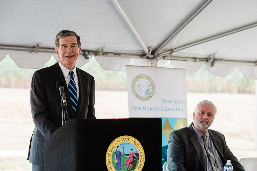 Governor Roy Cooper speaks at the announcement of a new industrial hose manufacturer warehouse at the Pender Commerce Park last fall as Pender Chairman George Brown looks on. (Port City Daily photo/Mark Darrough)