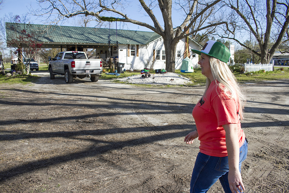 AJ Stanaland walks past the 1935 home she grew up on toward a late 1890s flag stop her great great grandfather built, which her family is renovating with plans to host monthly farm-to-table events. (Port City Daily photo/Johanna F. Still)