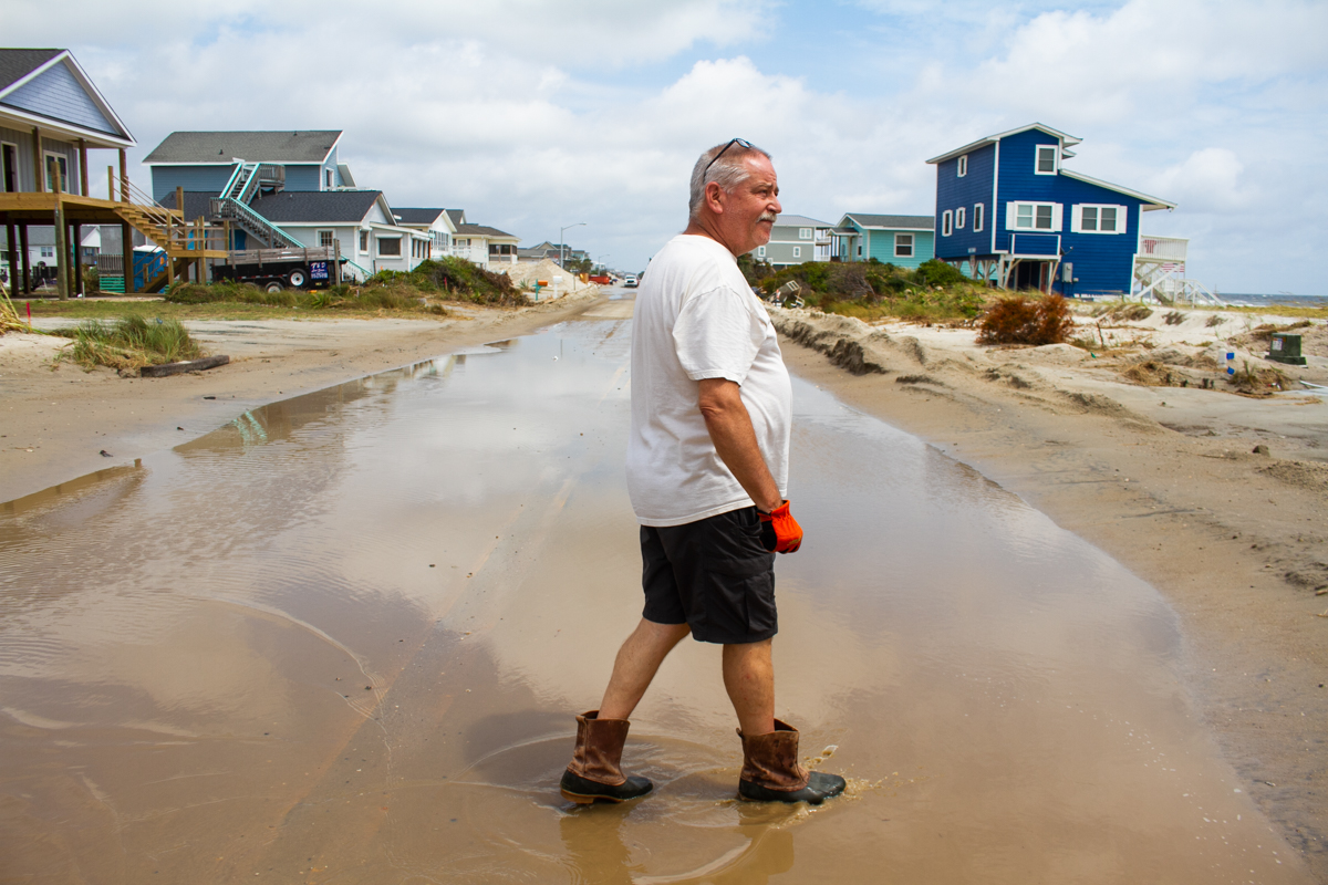 John Clift walks across flooded Beach Drive on Oak Island after Hurricane Isaias. "They should have never built on these lots," he said of the oceanfront homes that removed dunes in front of his house. (Port City Daily photo/Johanna F. Still)