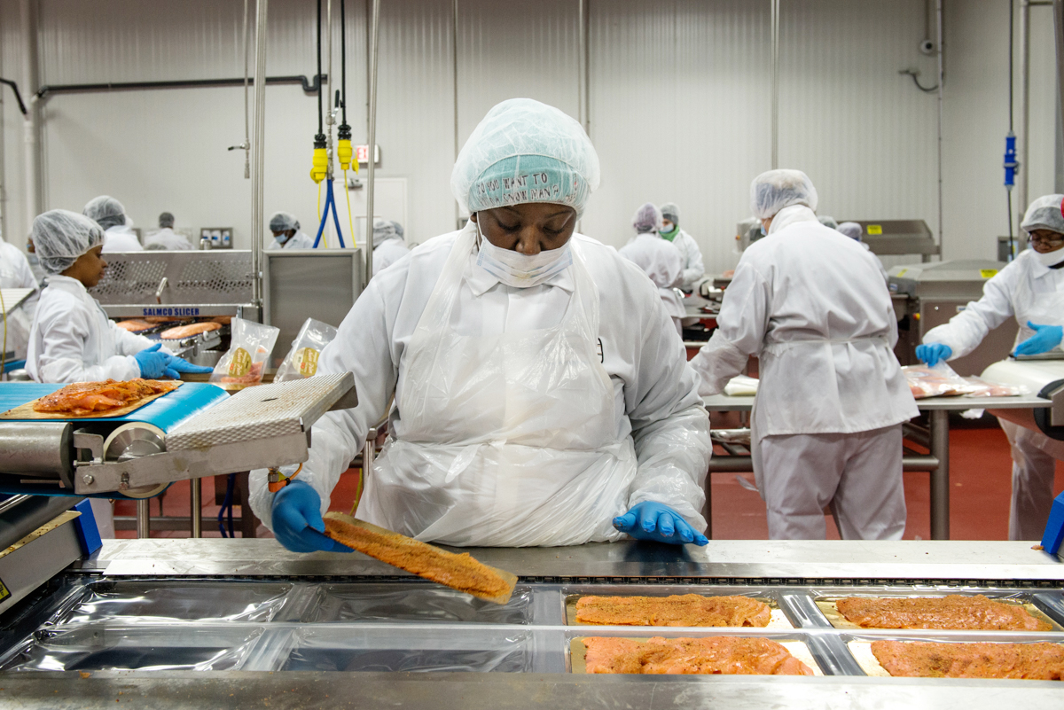 An Acme Smoked Fish production associate loads trays of sliced, cold-smoked salmon into packaging before it gets vacuum sealed and delivered to grocery stores across the nation. (Port City Daily photo/Courtesy Acme Smoked Fish)