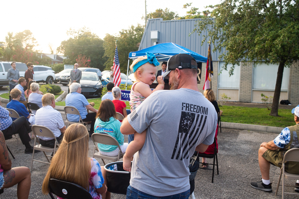 A rally attendee holds his daughter as Congressman Rouzer speaks Wednesday evening. (Port City Daily photo/Mark Darrough)