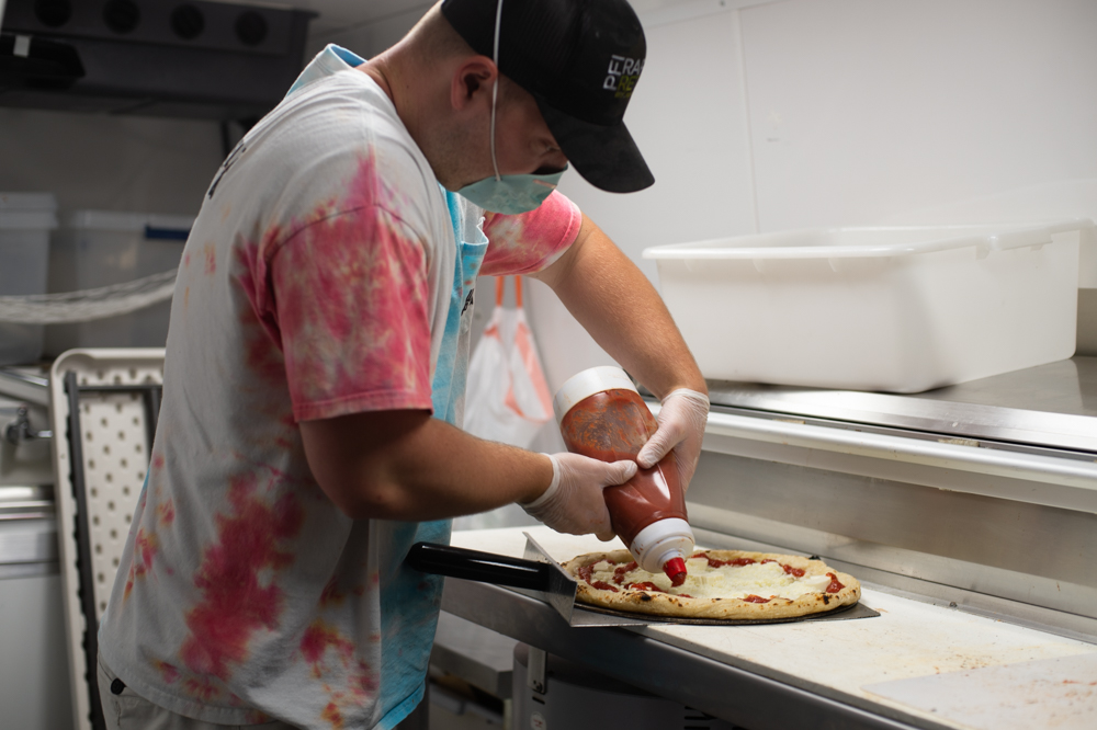 Collin McManamy, a Wheelz Pizza employee, works in the food truck kitchen Monday night. (Port City Daily photo/Mark Darrough)
